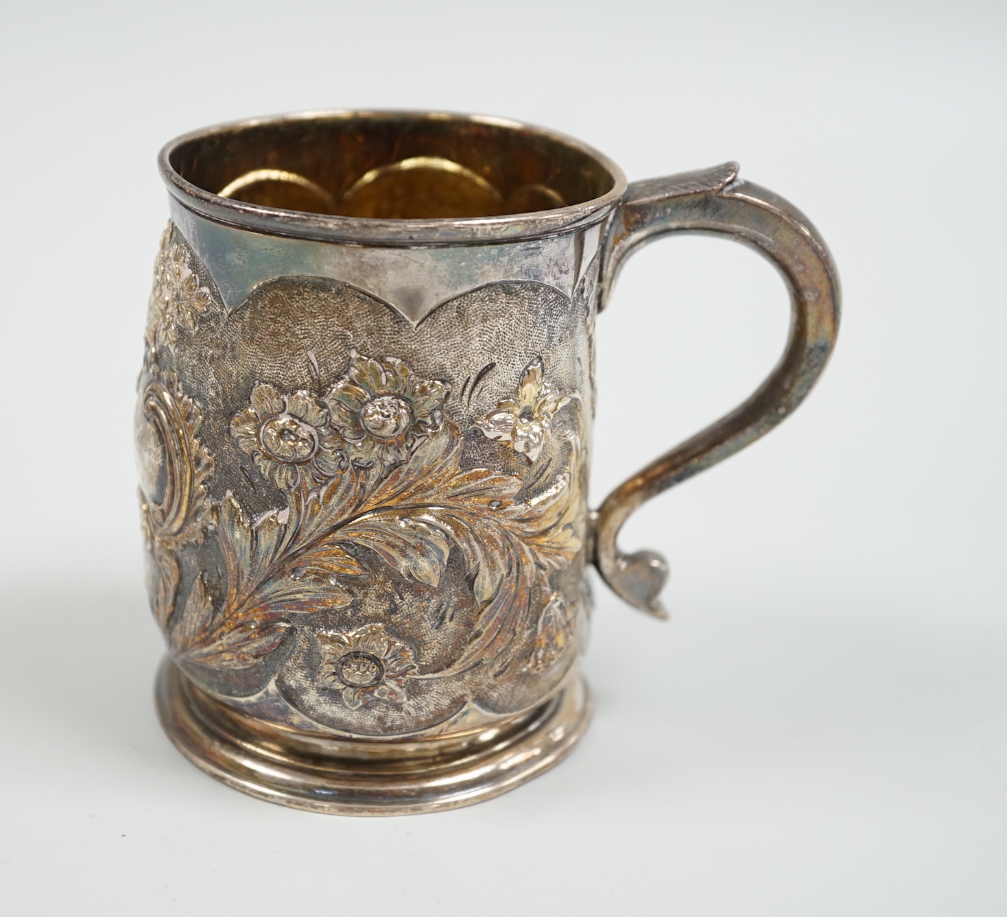 A George II silver mug, with later embossed decoration, makers mark rubbed, London, 1724, 9cm, (a.f.) 6.1oz.